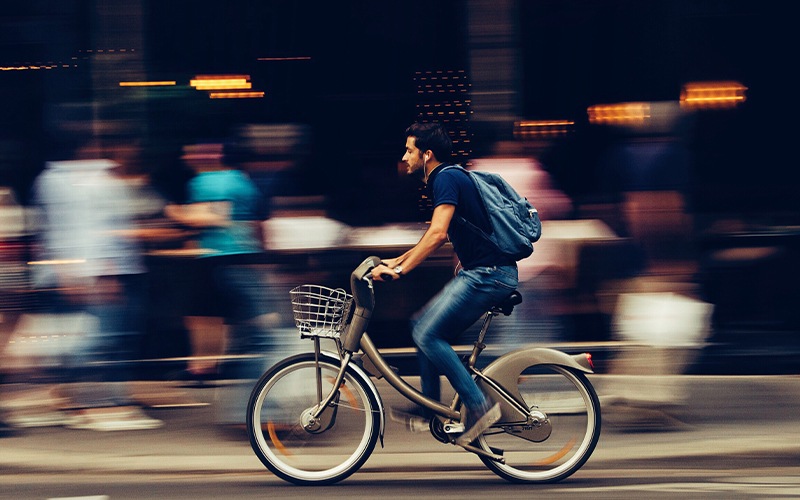 Man rides his bike down a busy sidewalk
