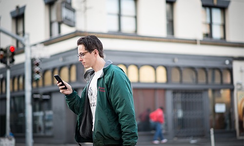 Man walks down the street reading his phone